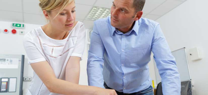 Två kollegor i samtal vid ett skrivbord på en arbetsplats